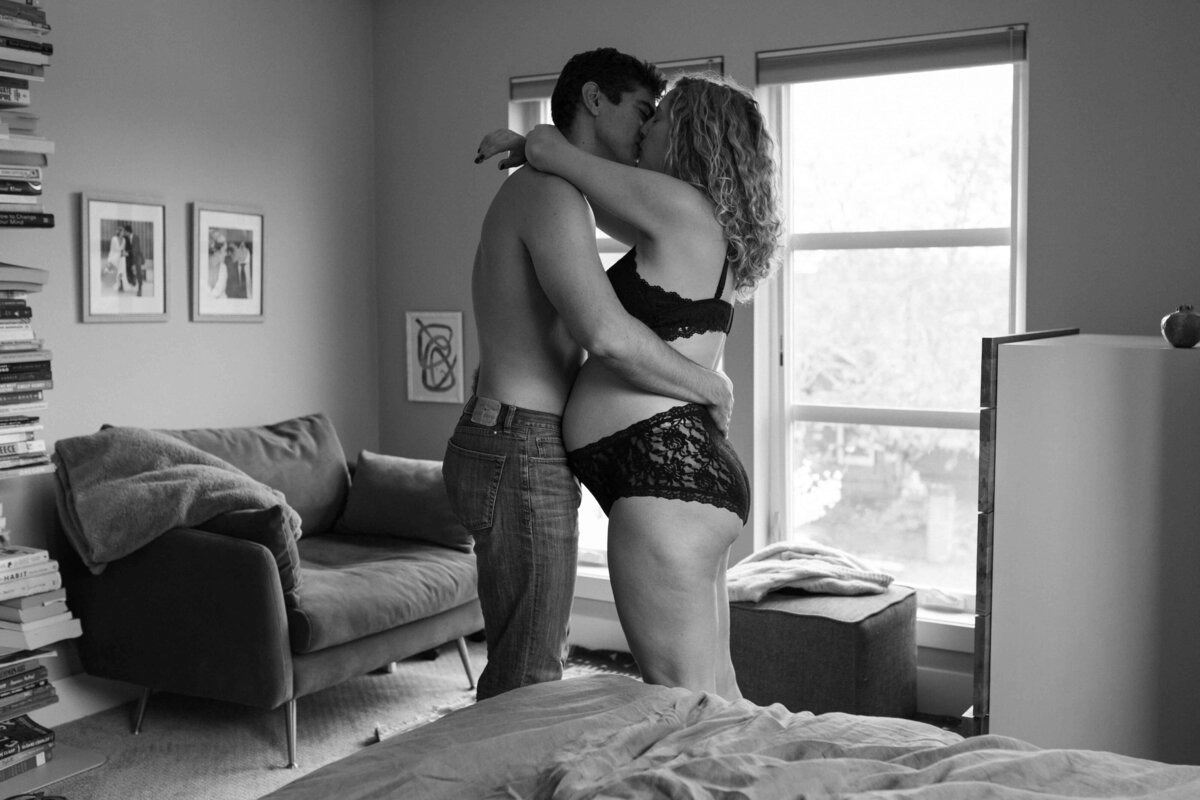 Black and white image of soon to be parents kissing during a home maternity photoshoot in Portland, Oregon.