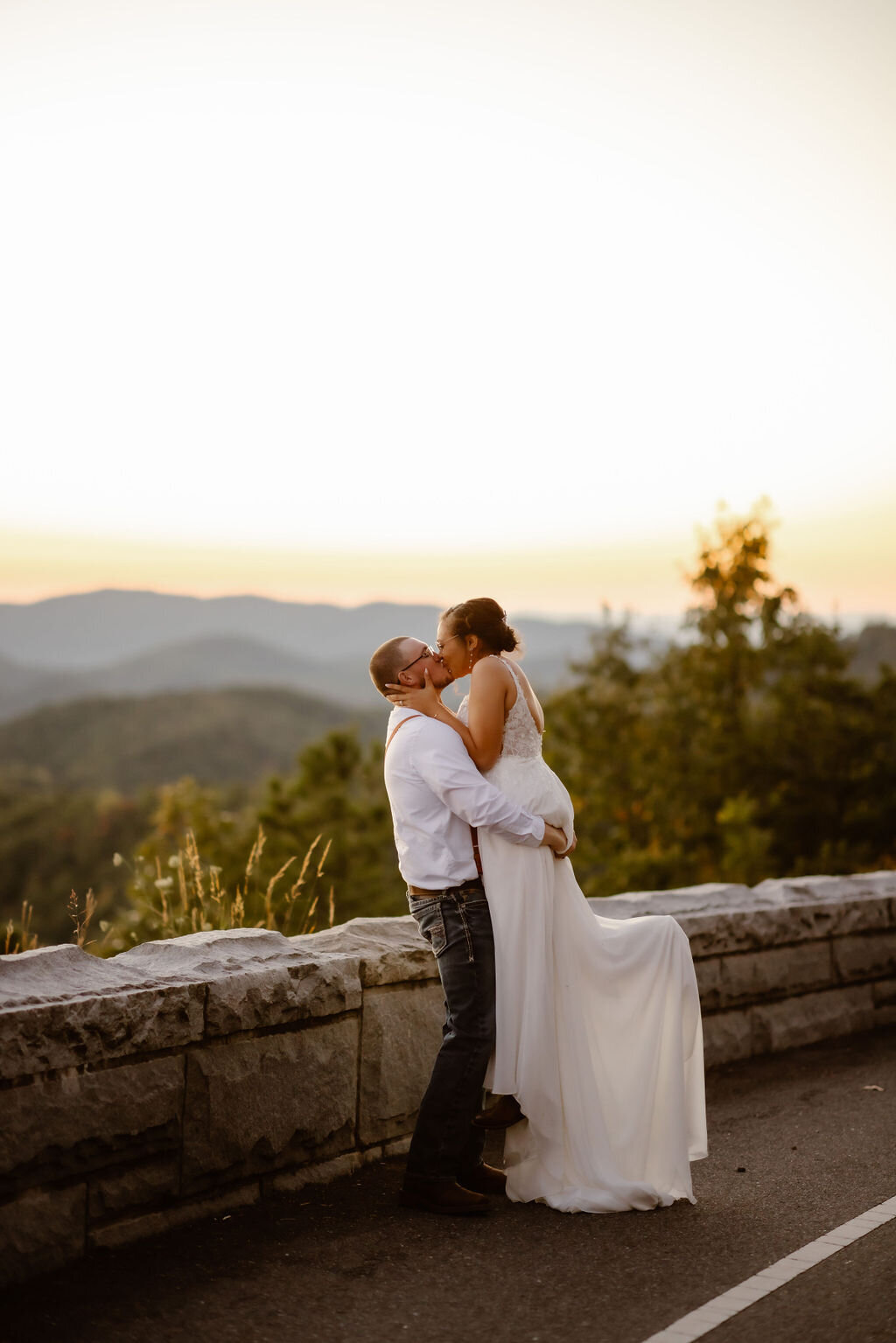 groom picks up his bride as she pops her feet behind her and kisses her groom passionately for their Smoky Mountain elopement in the Foothills 