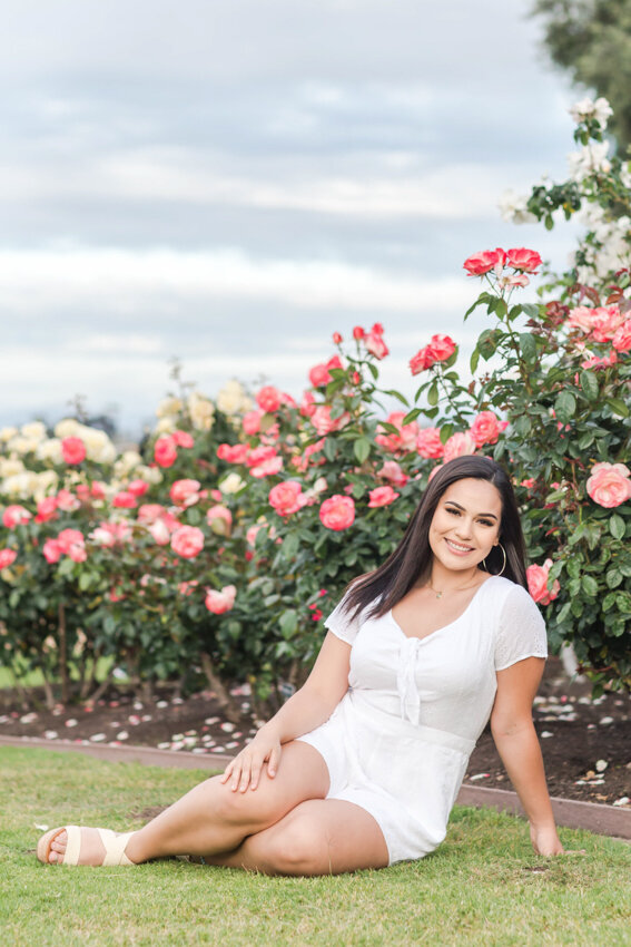 Senior girl sittingn in  rose garden San diego