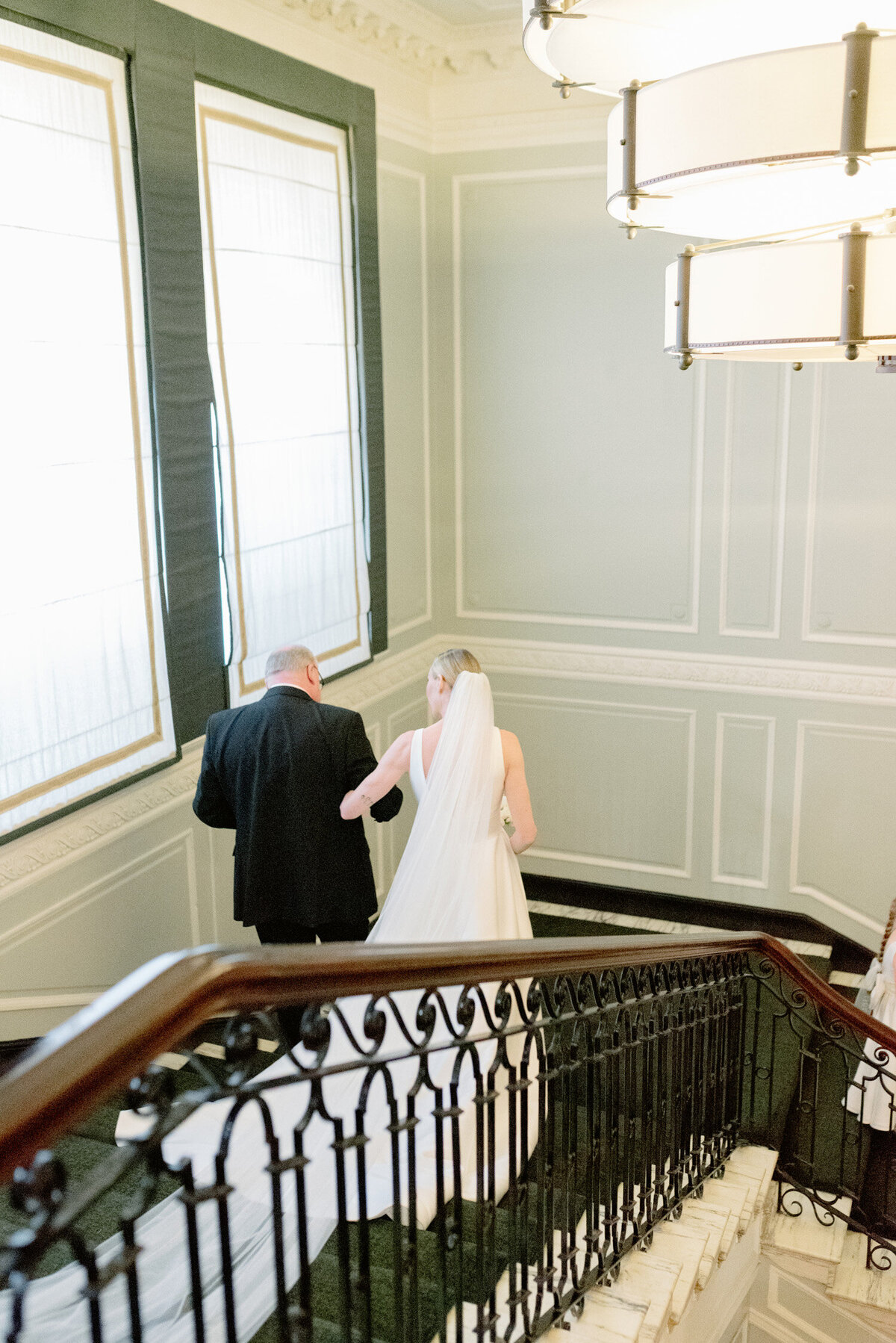 Father walking his daughter down the main staircase of Gleneagle Hotel. Emotive black and white image of a Father seeing his daughter for the first time on the morning of her Gleneagles wedding.  Image by luxury wedding photographer, Jill Cherry Porter.