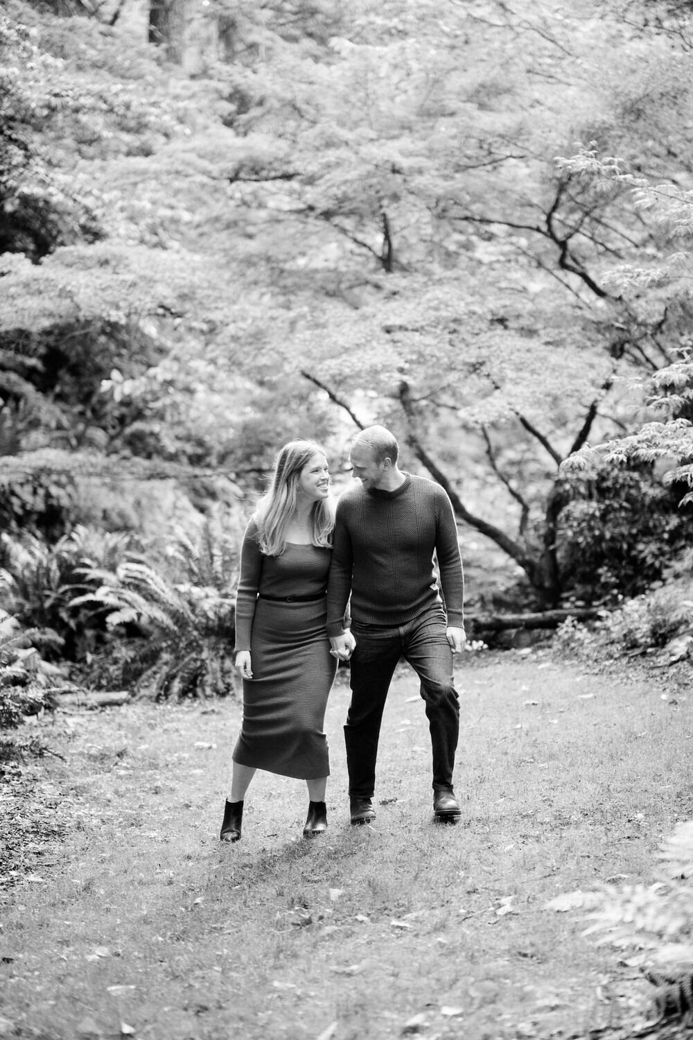 Couple holding hands, walking and laughing during an engagement photo session