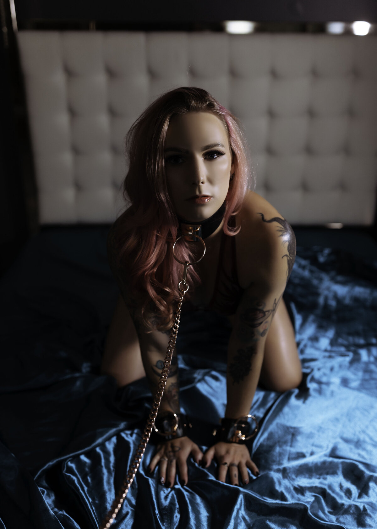boudoir photo woman kneeling on blue sheets with bondage leash