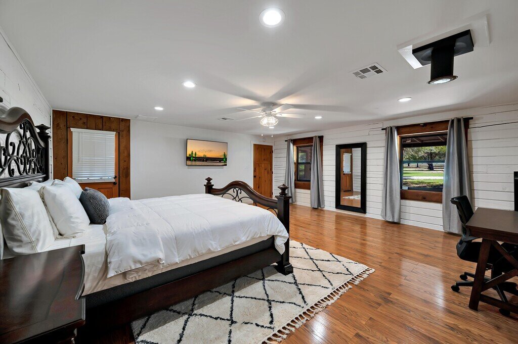 Master bedroom with King size bed, backyard access, flat screen TV, and private bathroom in this four-bedroom, three-bathroom cabin with private garage, firepit, grill, and wi-fi just outside of Waco, TX