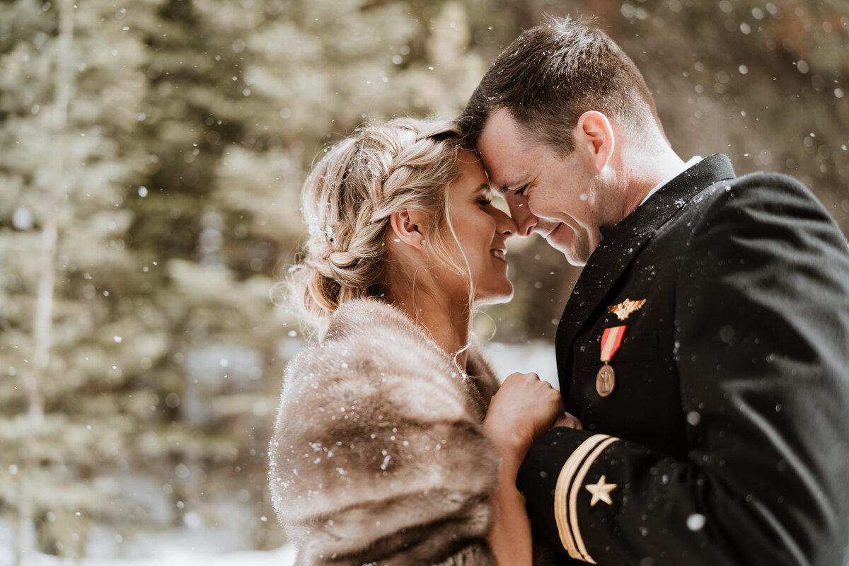 Bride and groom share intimate winter moment with snow falling during Breckenridge wedding.