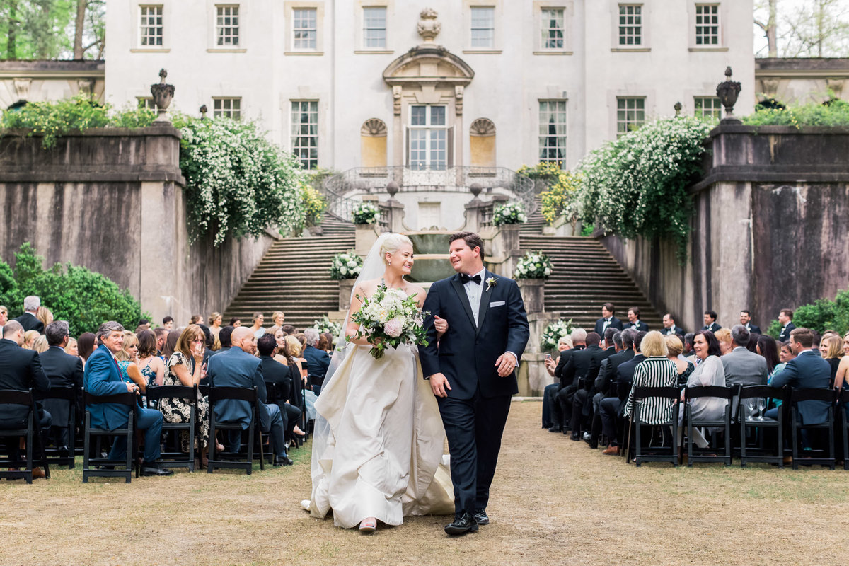 A joyful Swan House bride and groom exit their wedding ceremony as husband and wife. Photo by luxury destination wedding photographer Rebecca Cerasani.