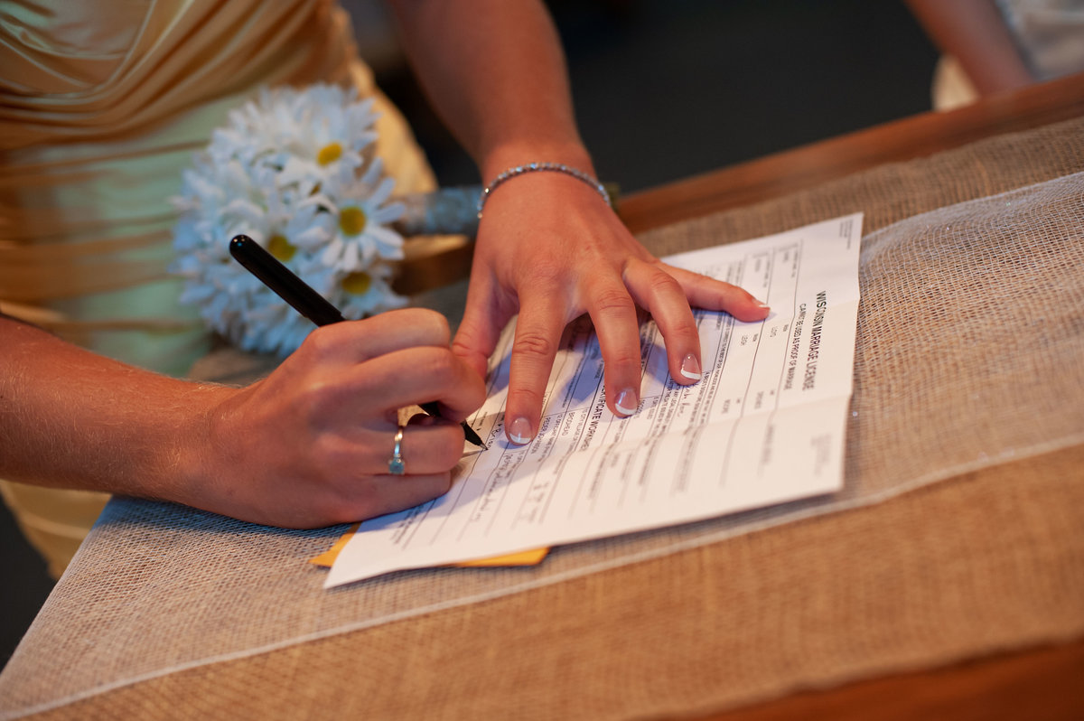 hands holding pen signing marriage certificate