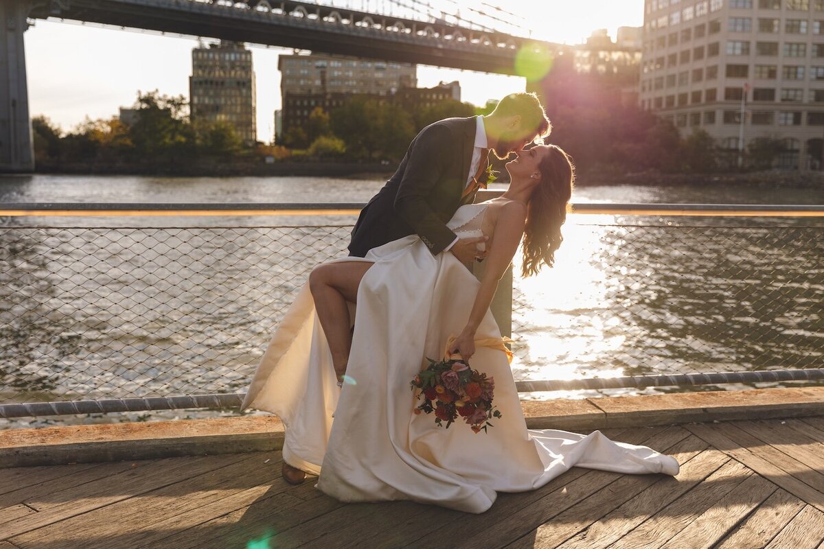 Groom spinning bride in wedding dress by the East River