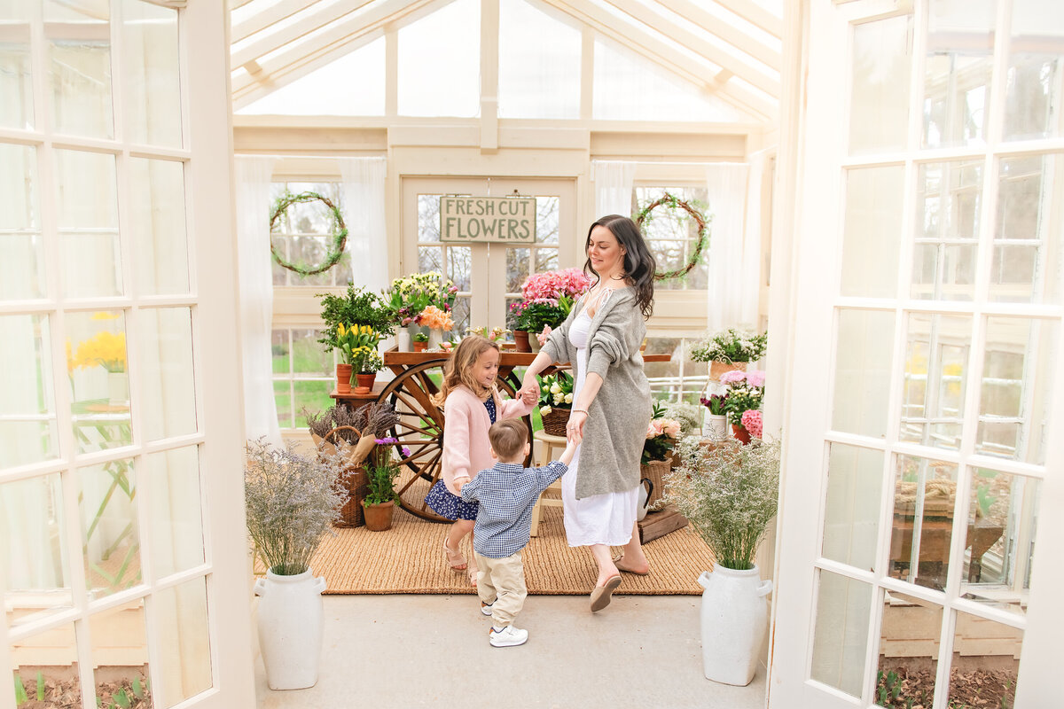 Family greenhouse photo with mother dancing with children surrounded by spring flowers | All Who Wander Flower Farm in Dundas Ontario