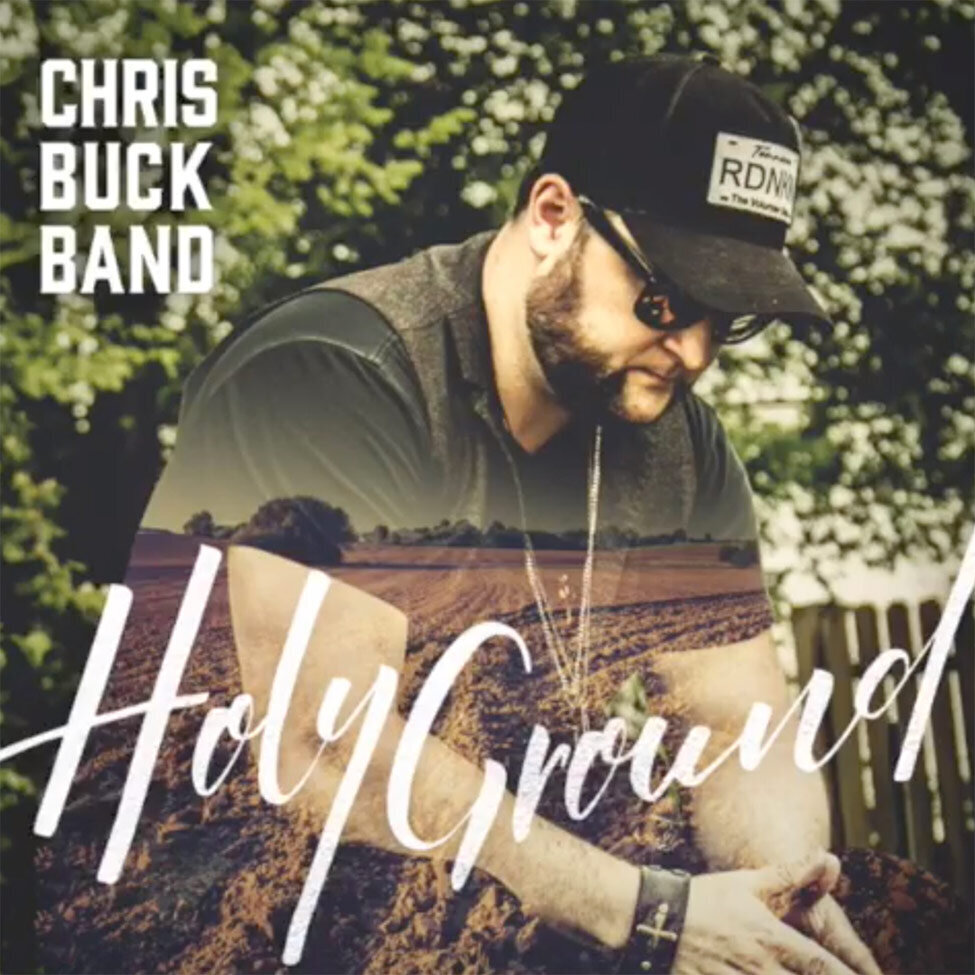 Single Cover Nashville Title Holy Ground Artist Chris Buck Band Singer seated hands clasped together while looking down wearing sunglasses and hat tree with leaves behind him farmland superimposed on his tshirt and body