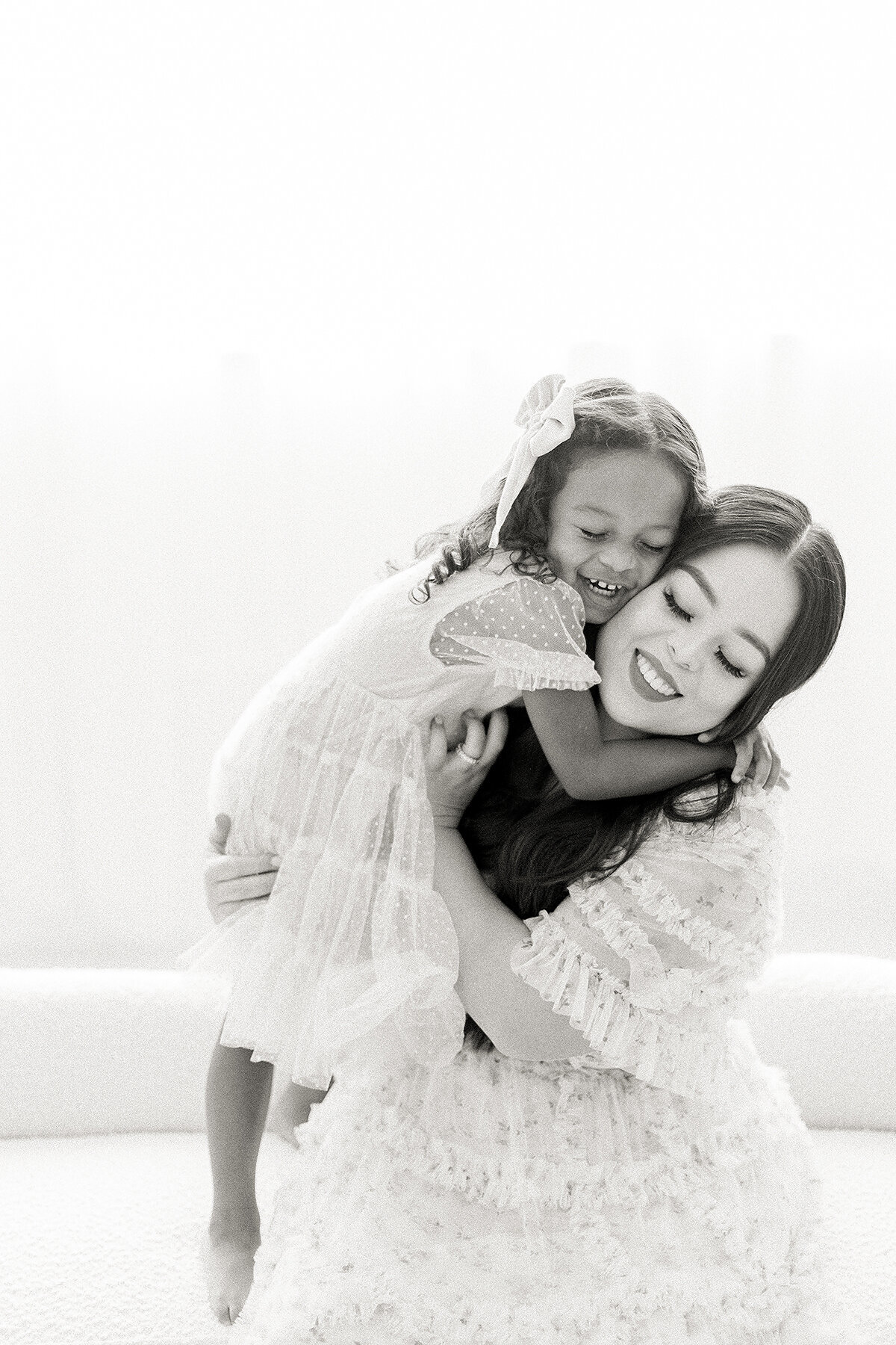 Black and white close up photo of a mother being hugged by her daughter for an in studio session.