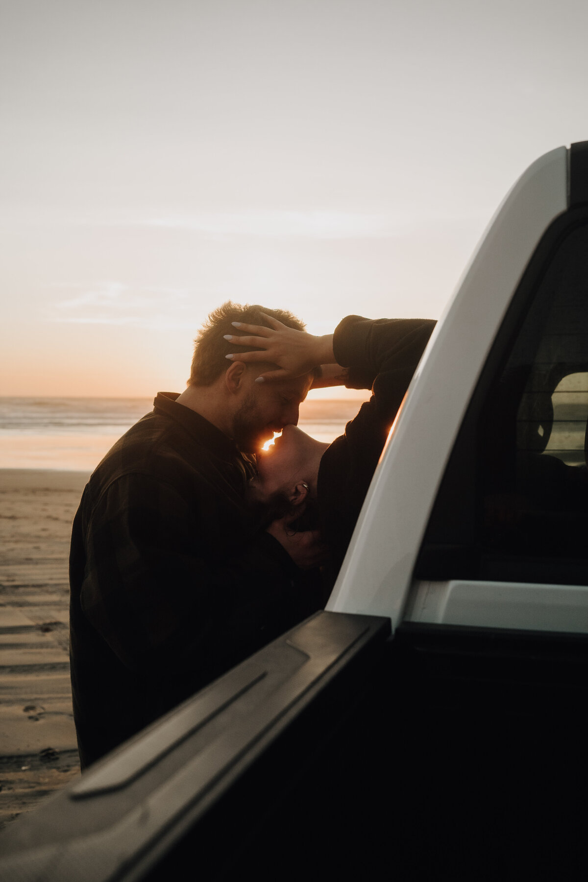 Engaged couple kissing in truck on a beach 