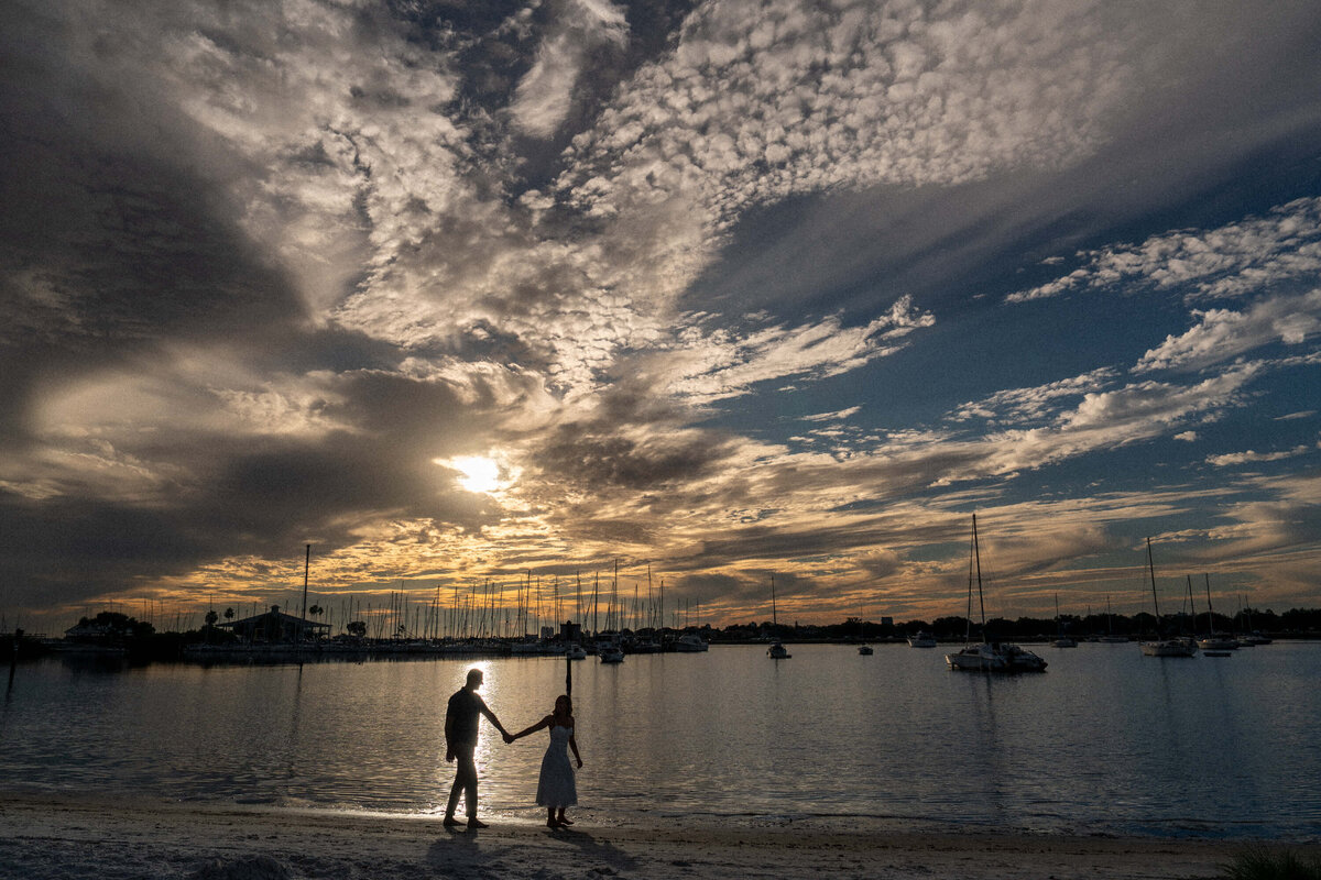 Silhouetted couple walking along a marina during a dramatic sunset at Davis Island Beach