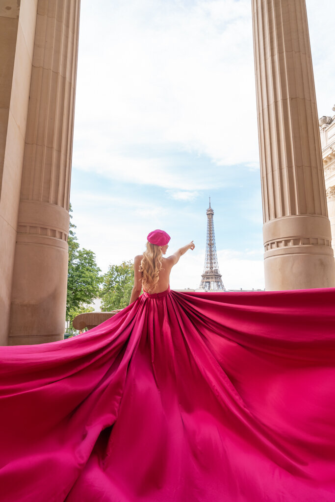 Creative flying dress photo at Palais Galliera with woman in pink gown pointing at Eiffel Tower