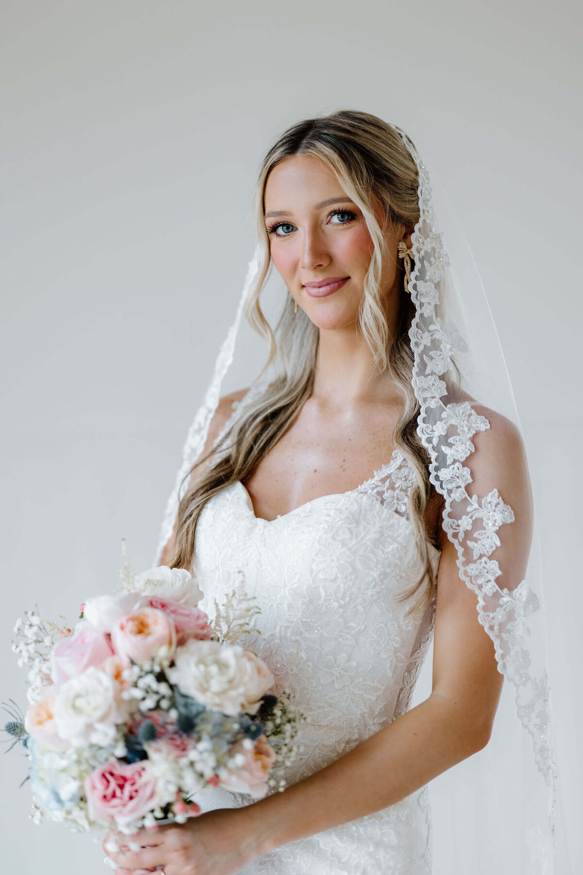 bridal portraits in white lace wedding gown, lace veil, and summer inspired bouquet