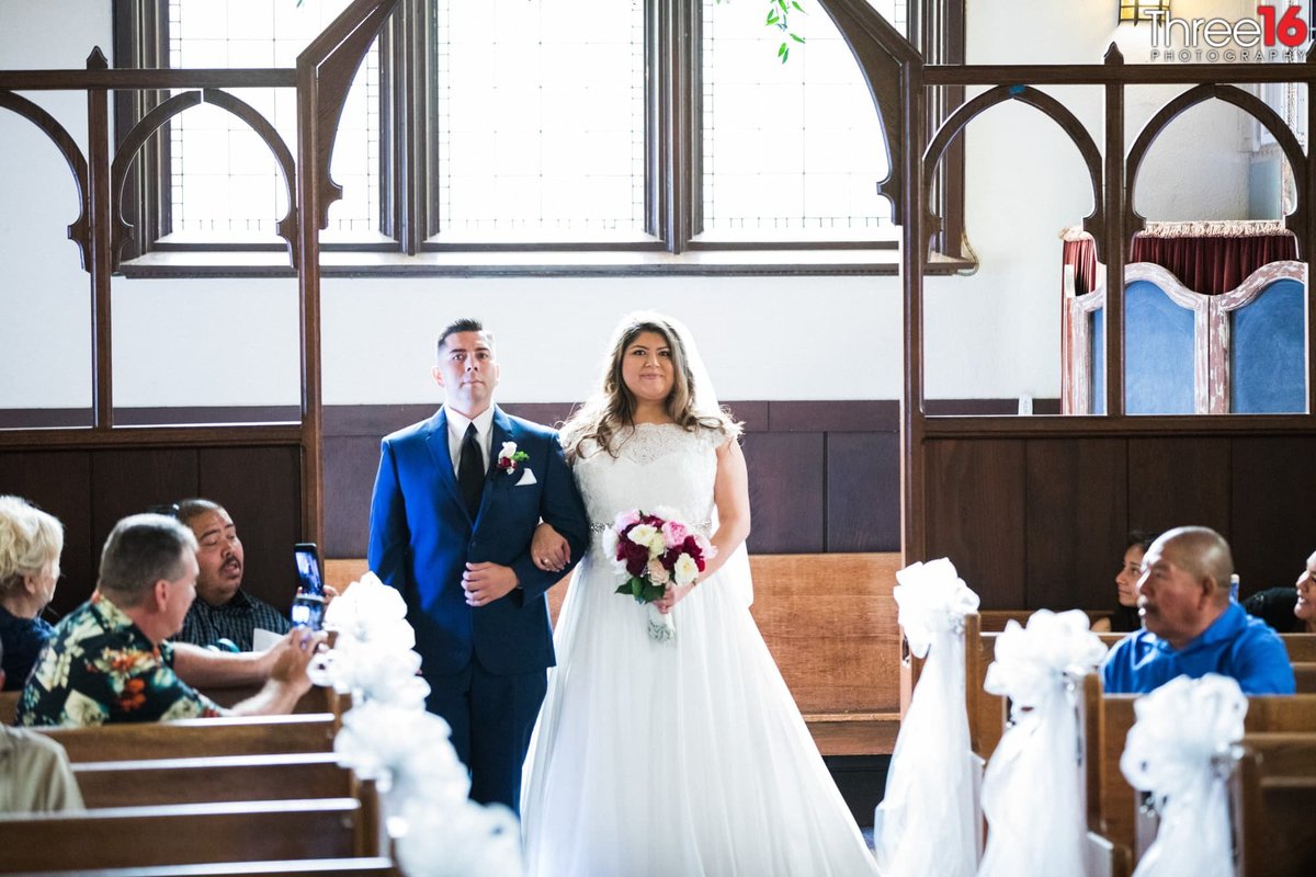 Bride being escorted down the aisle at The Chapel of Orange