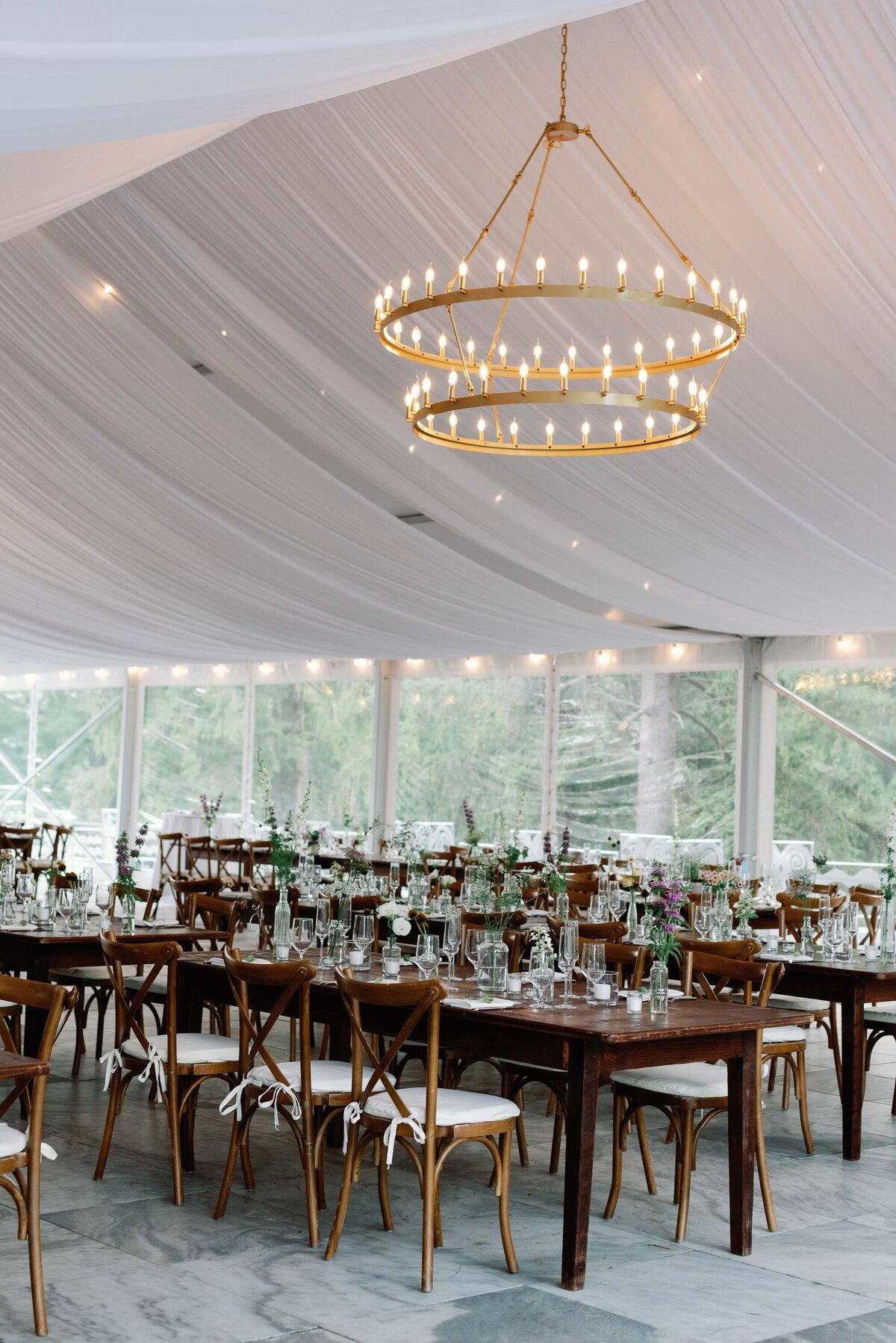 indoor reception at wilburton inn with farm tables, glassware, and lit chandeliers