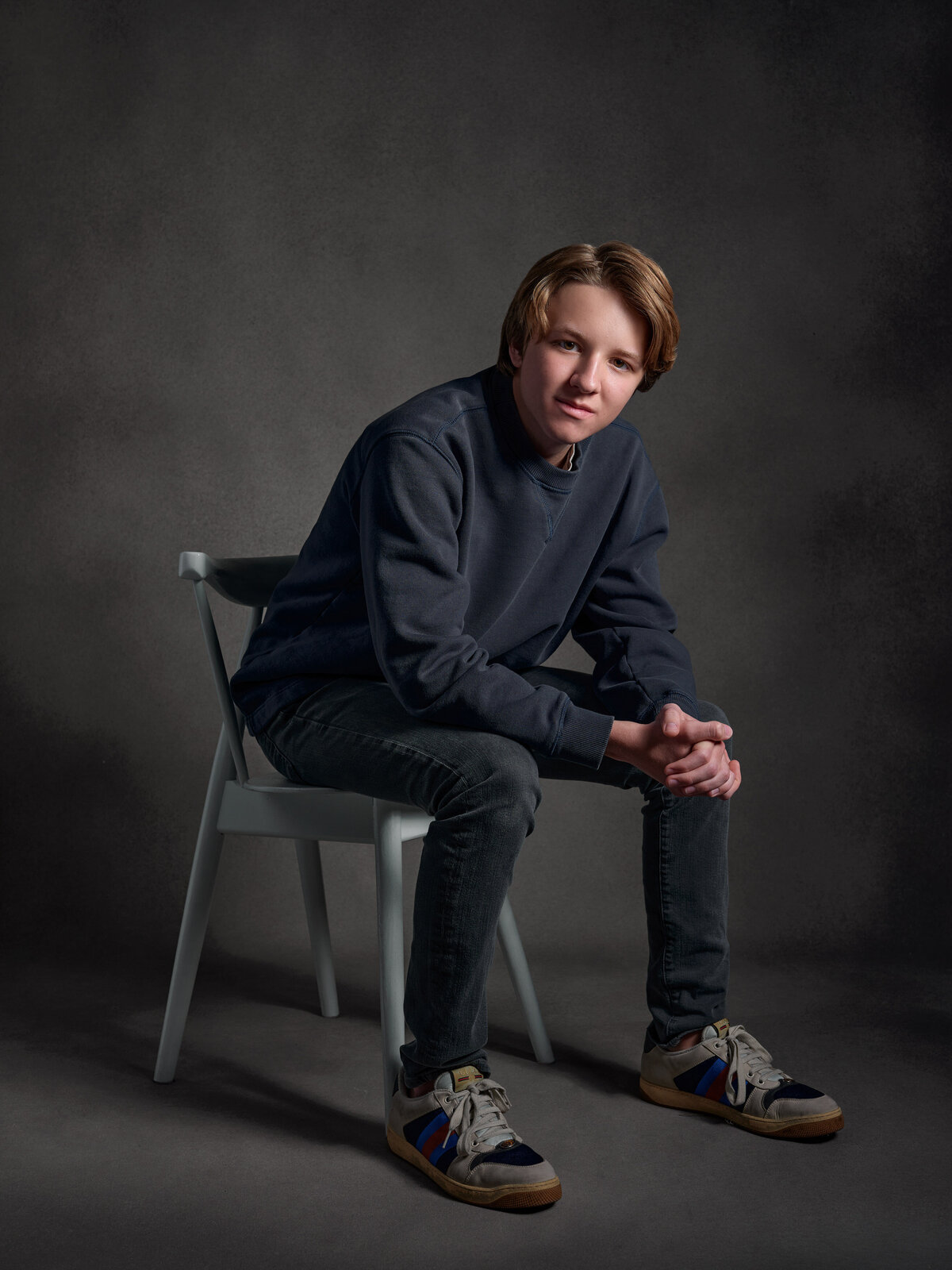 A boy sitting in a chair leaning on his legs