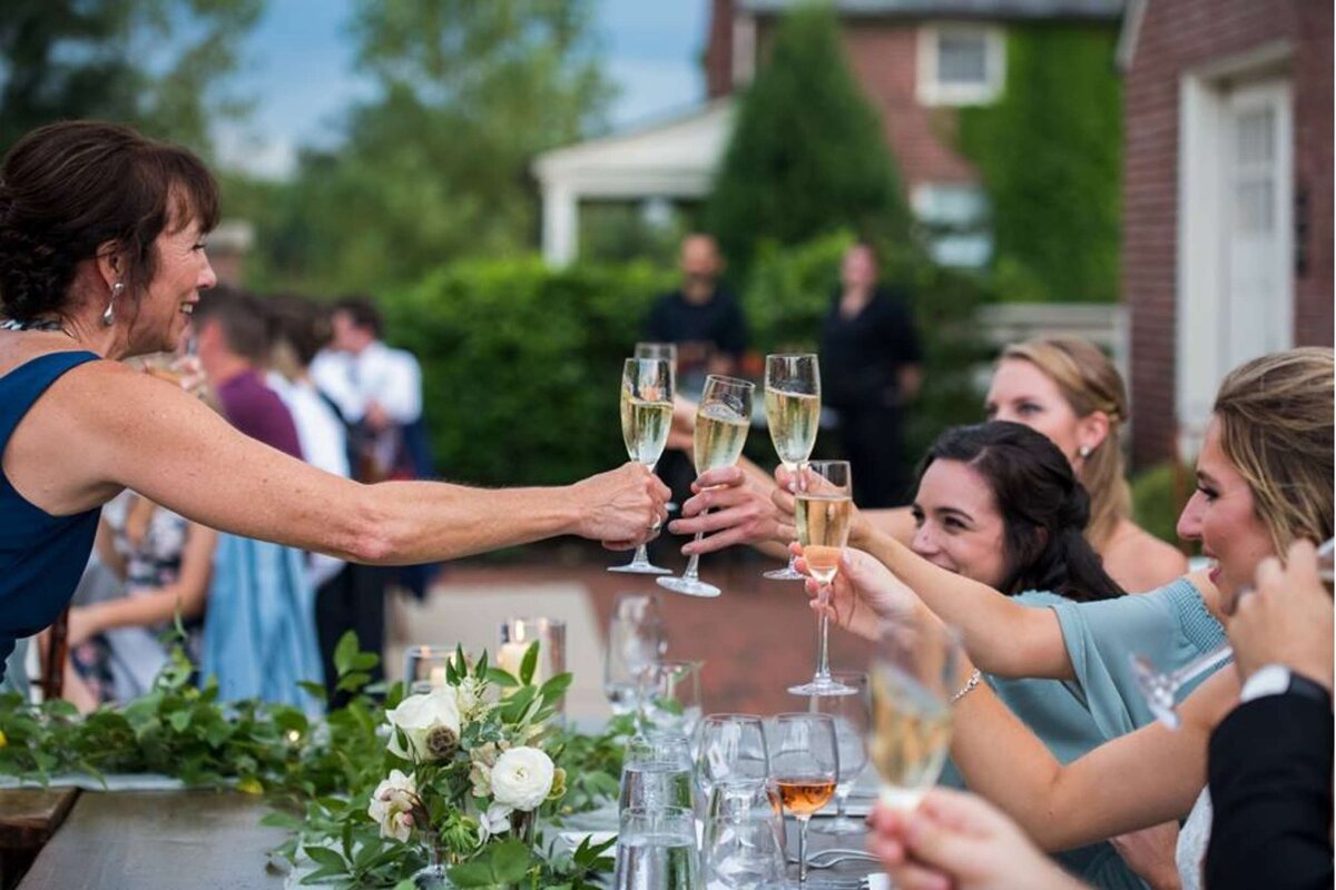 Guests toast on the outdoor patio during dinner at a luxury Italian inspired Chicago North Shore wedding.