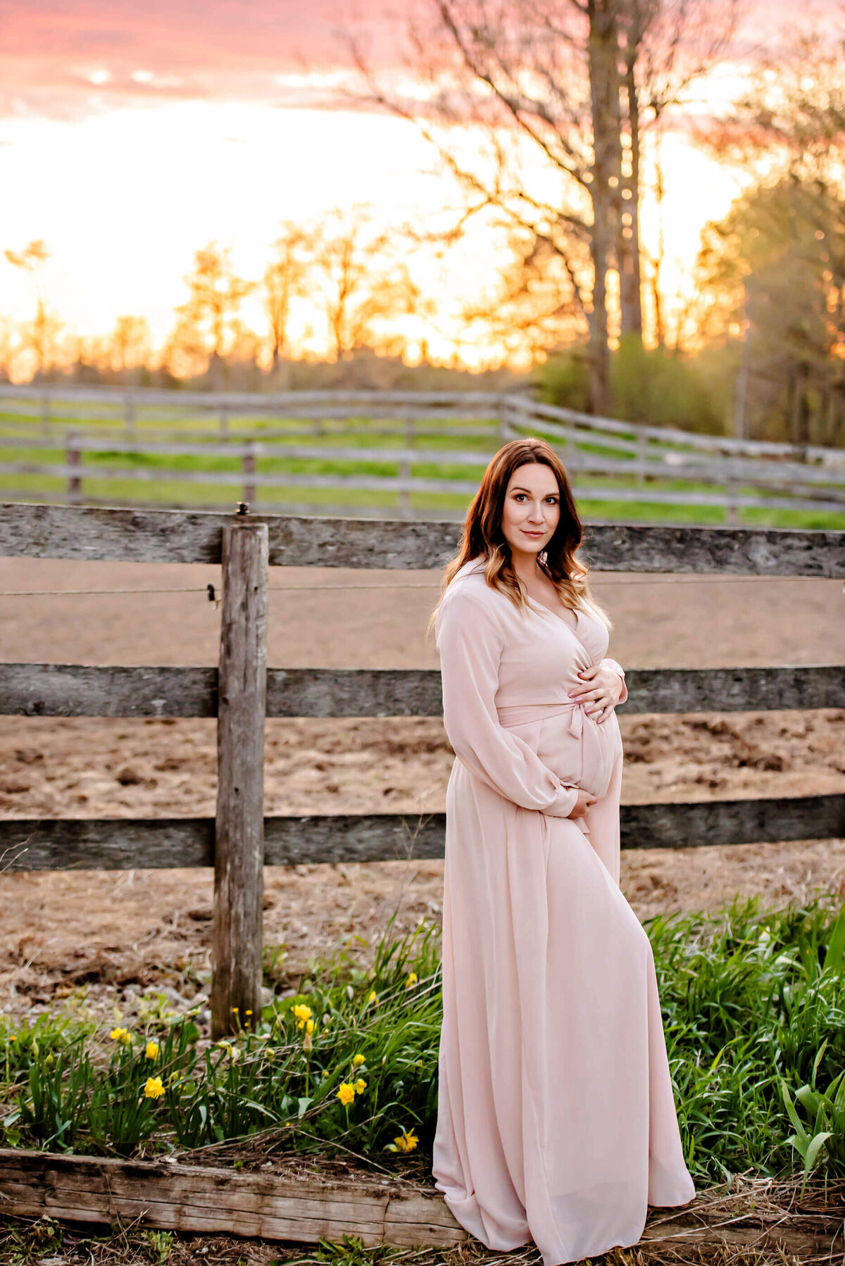 pregnant woman standing in front of a wood fence for her outdoor maternity photos