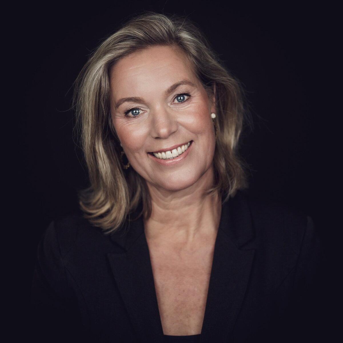 Blond model tegen een zwarte achtergrond.