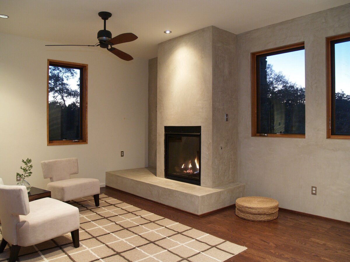 home sitting room with fireplace and geometric rug. wooden ceiling fan in living room of custom home.