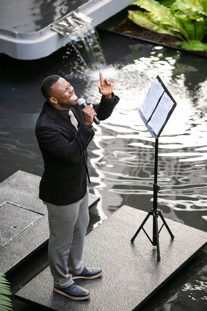 A man singing on a small platform in a pond