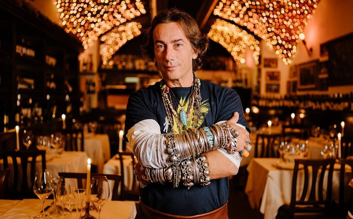 The owner of Florentine restaurant La Giostra standing in front of candlelit dining room. 