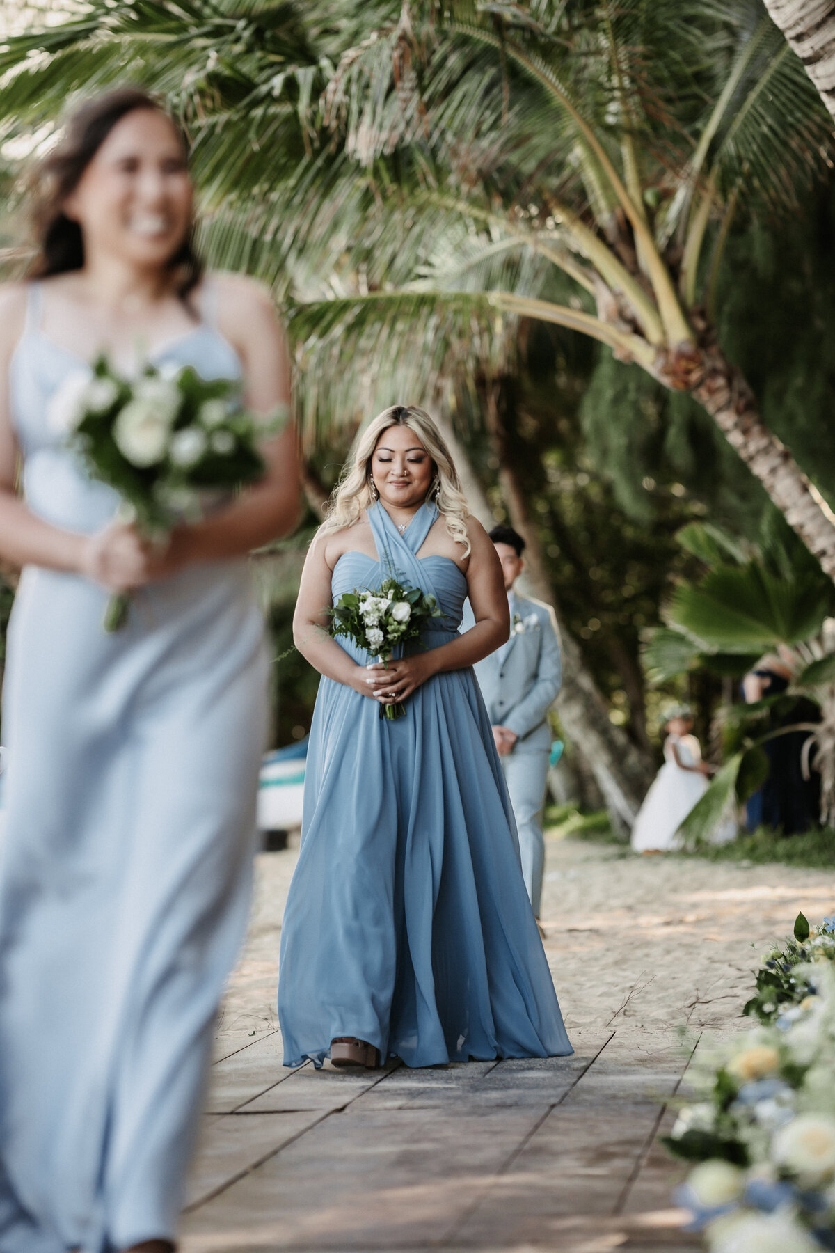 Bridesmaids walking down the aisle wearing hues of blue dresses