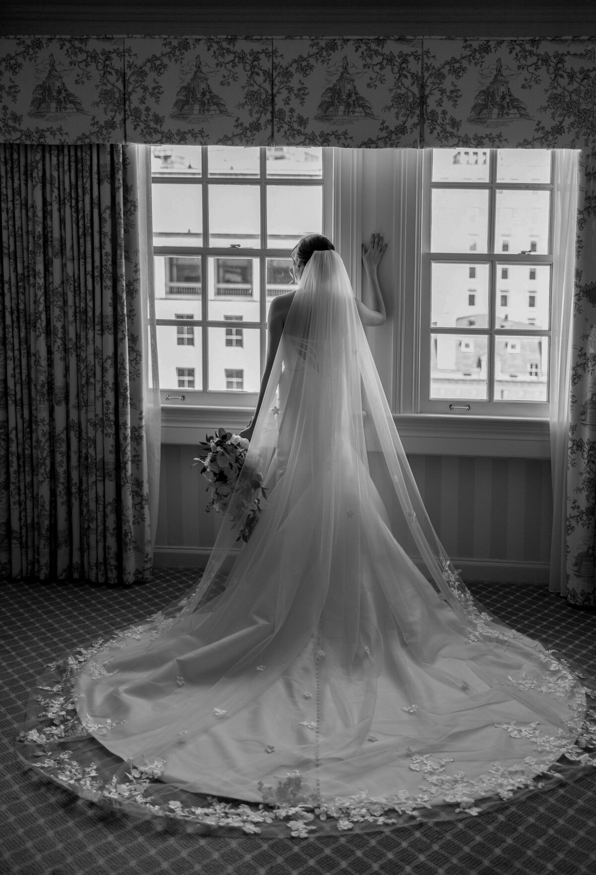 bride-wearing-long-veil-and-looking-out-window