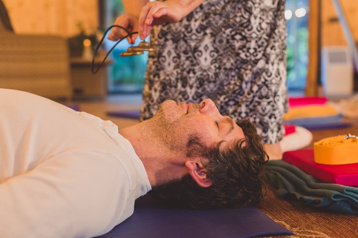 A man lying down on a mat with his eyes closed