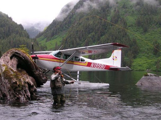 Man standing in the water in front of a small airplane