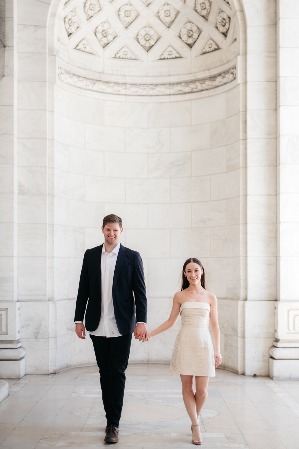 couple holding hands walking during NYPL engagement session