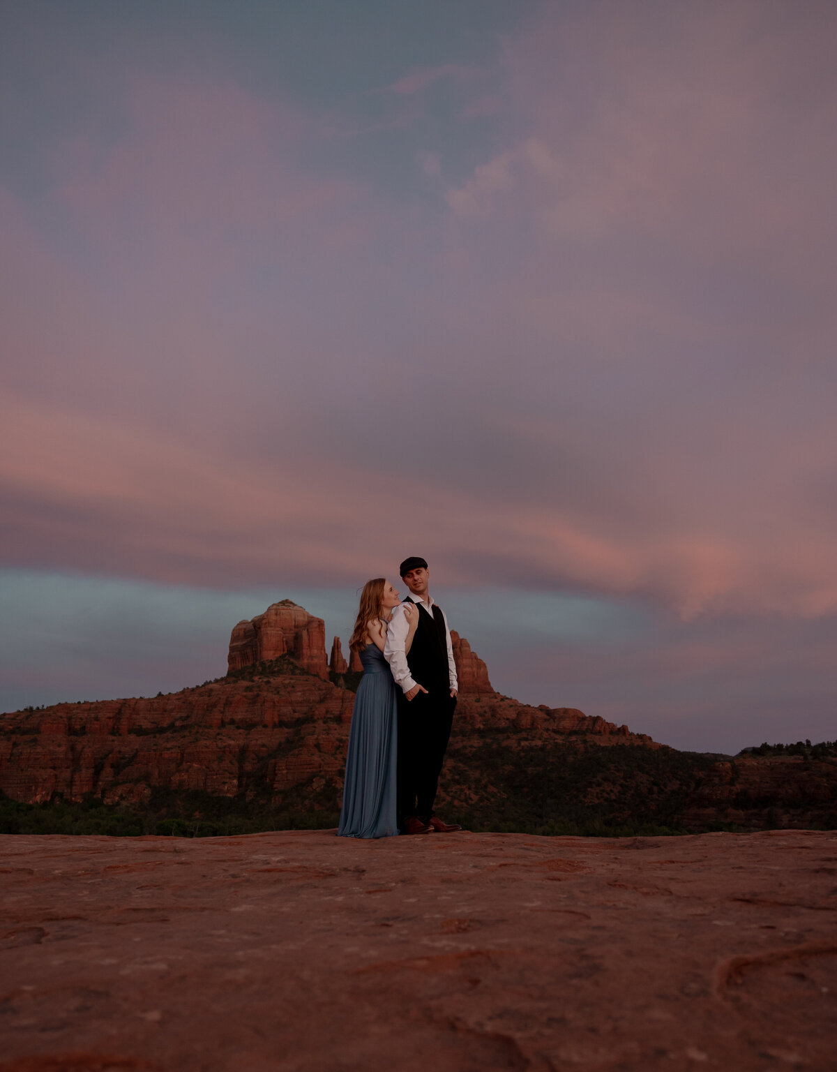 Couple standing against red rock backdrop during Sedona engagement session