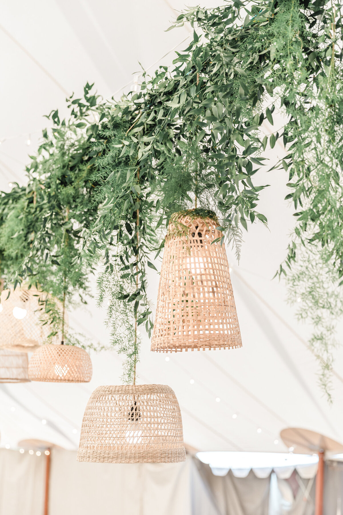 Rattan lanterns  hang from sail cloth tent at garden wedding