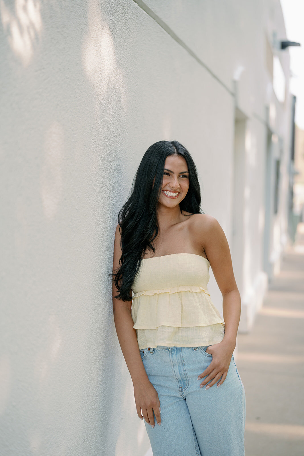 High school senior smiling in front of blooming hydrangeas during her downtown South Haven senior photography session.