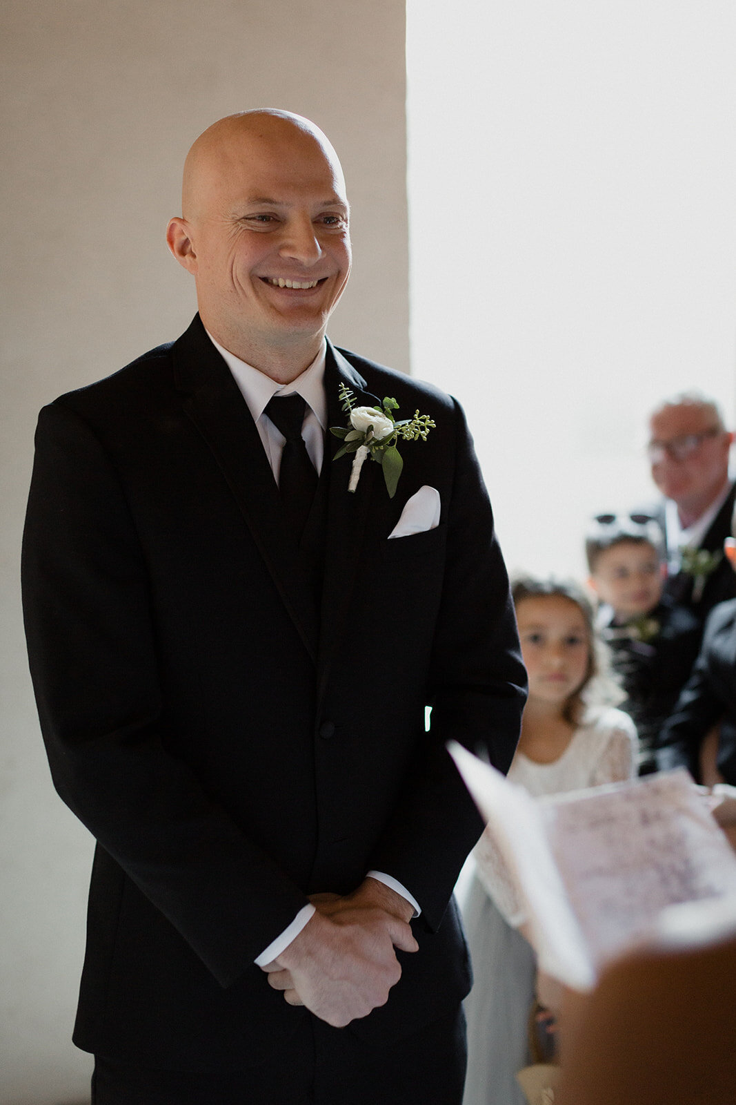 view of the groom smiling as he listens to brides vows