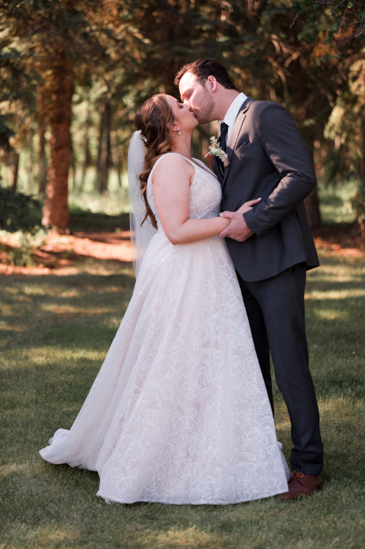 bride and groom kiss in friont of forest