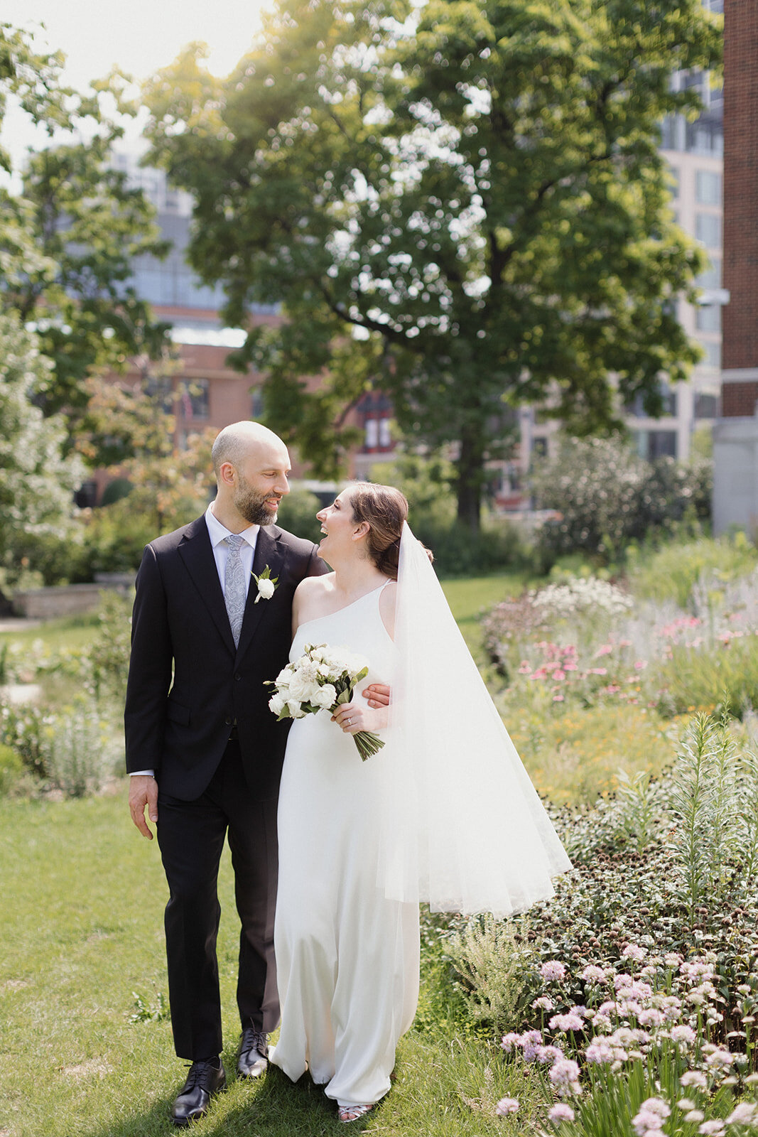 Couple walks in the summery garden looking at each other and laughing