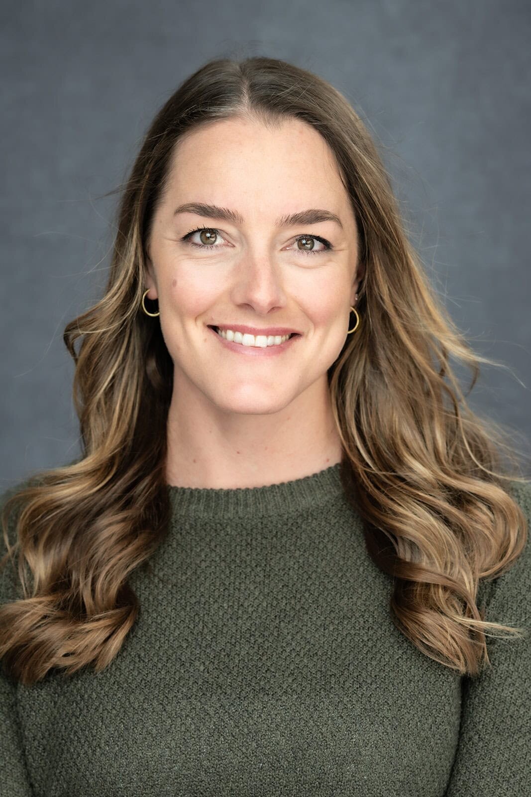 Young, athletic looking woman with long flowing hair smiling for a photo