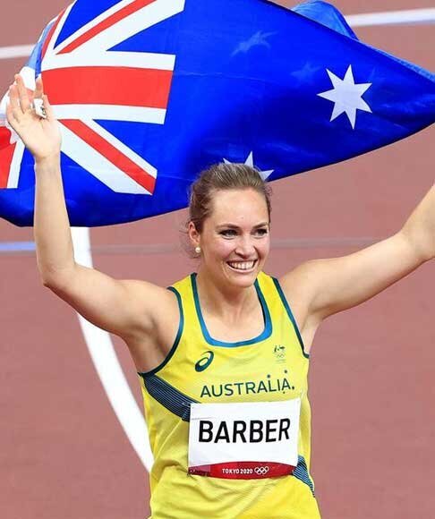 Australian athlete smiles while biting silver medal and holding sunflower bouquet on Tokyo 2020 Olympic podium