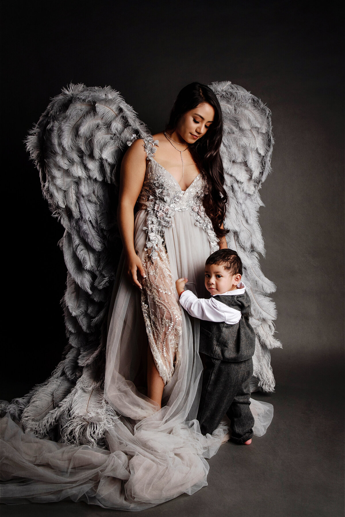 st-louis-family-photographer-mom-in-gray-gown-and-angel-wings-with-toddler-boy-in-gray-pants-and-vest