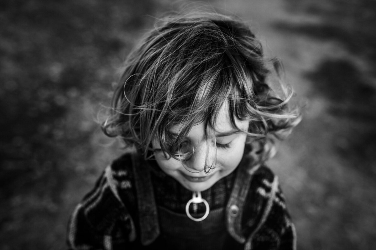 toddler boy with messy hair looking down with eyes closed at Oakland park
