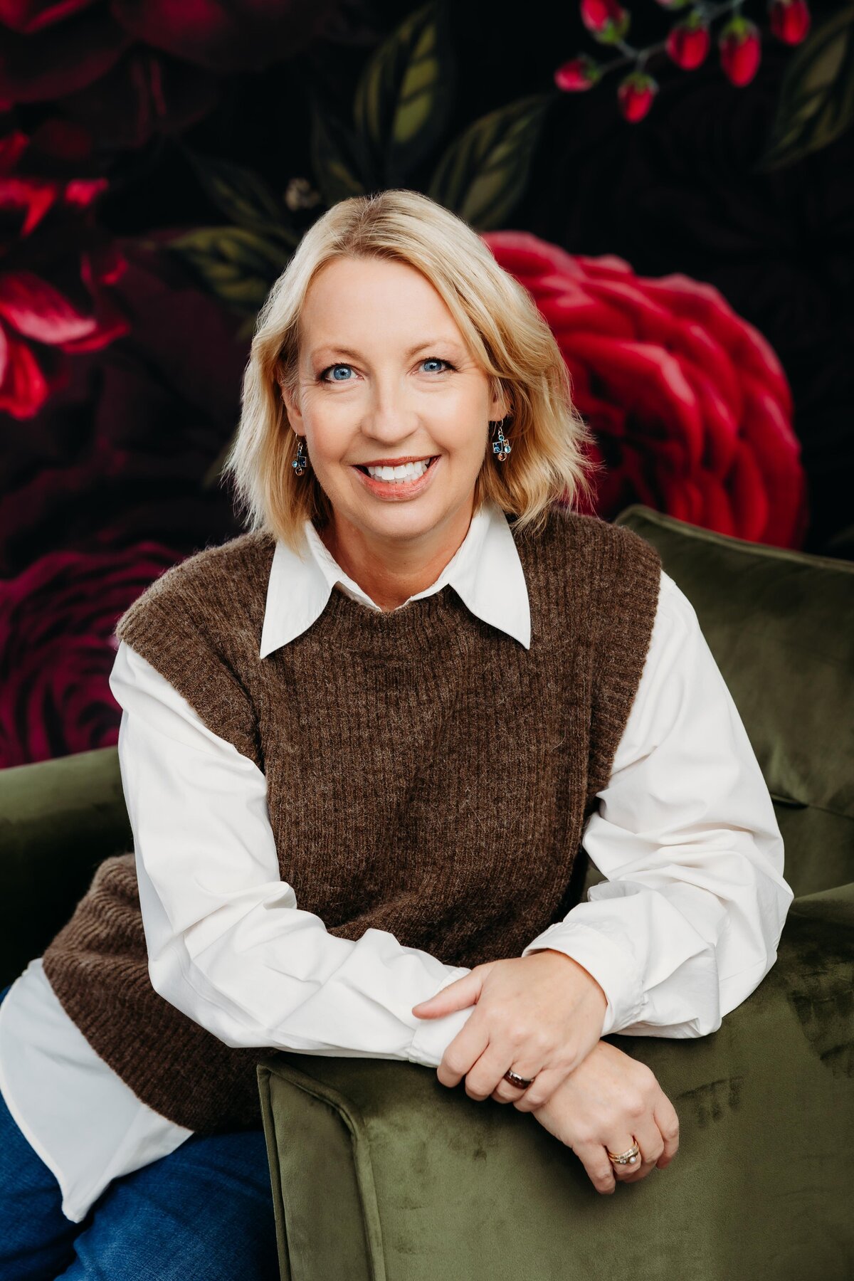 Woman posing with a floral backdrop for her headshots.