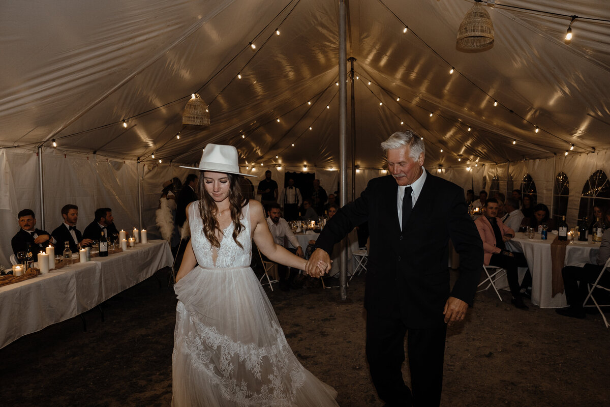 bride and groom holding hands in tent