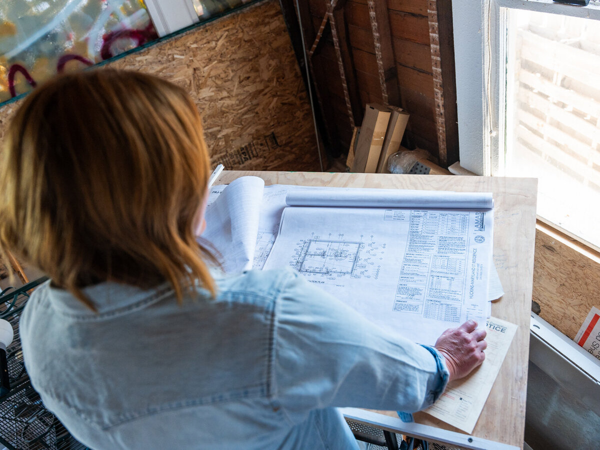 Overhead view of Courtney Murphy on a jobsite reviewing blueprints