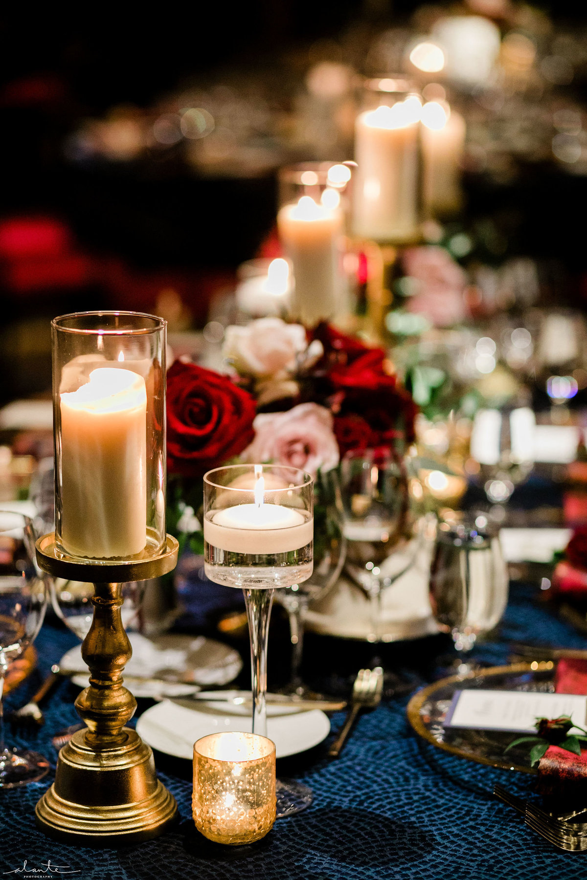 details of a winter wedding reception table with candles and red flowers
