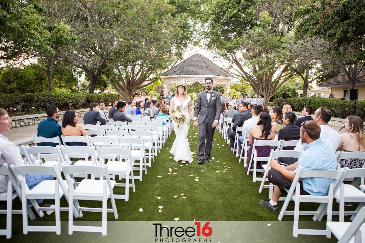 Newly married couple walk the aisle together after saying their I Do's