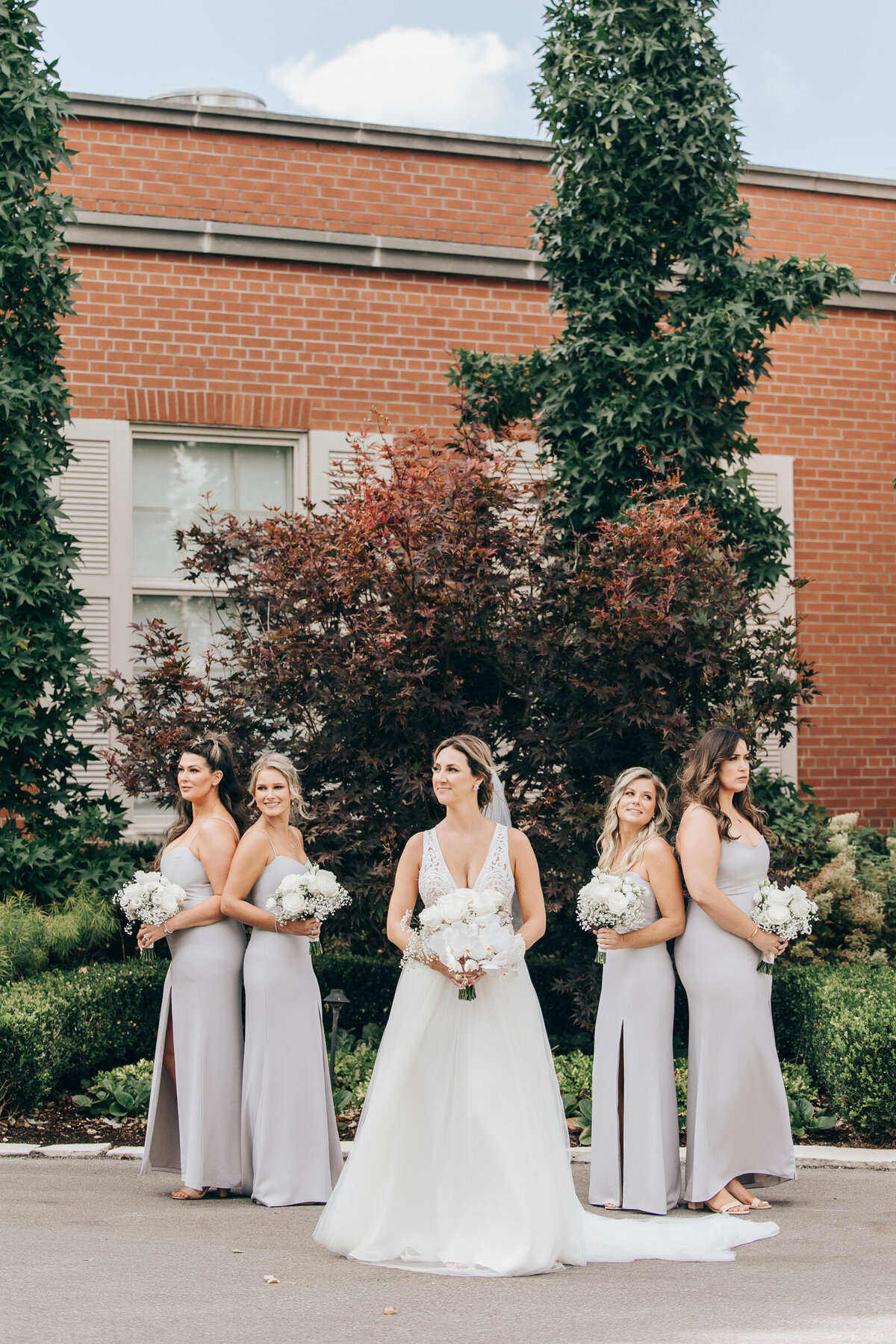Bridesmaids holding white bouquets posing for traditional photos