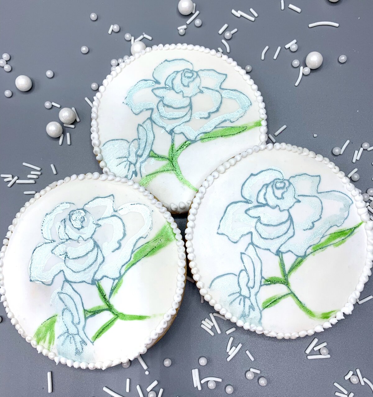 Stenciled blue roses on white iced sugar cookies
