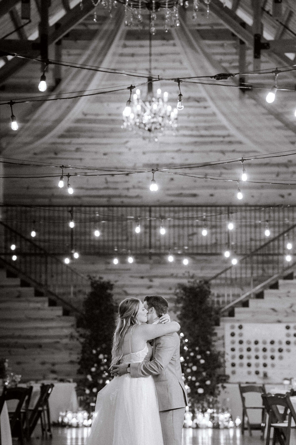 Newly married bride and groom share first dance at rustic winter wedding in Texas with string lights overhead